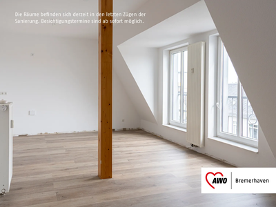 Wohnzimmer mit Stadtblick | ohne Balkon | © AWO Bremerhaven Heller Raum mit Holzbalken, großen Fenstern und hellen Holzböden in einem Dachgeschoss | © AWO Bremerhaven